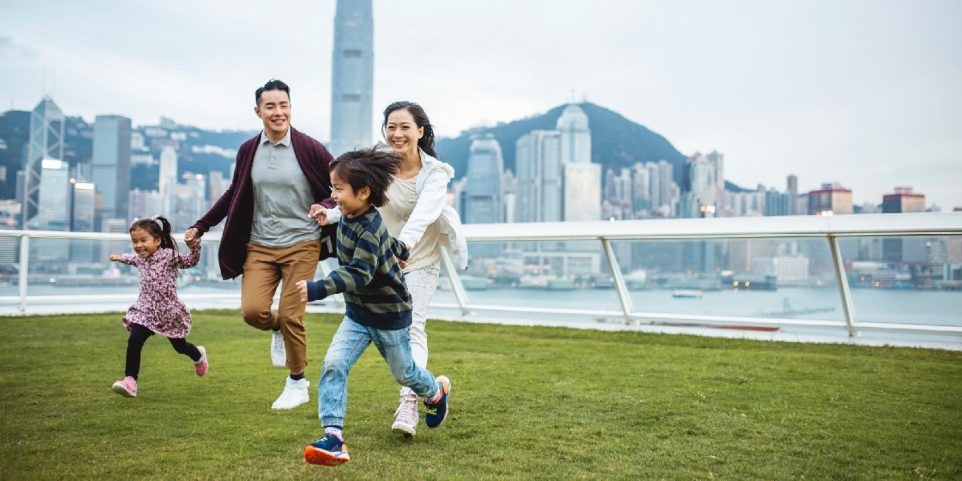 Asian parents and children running across the grass, engaging in a getaway for families.